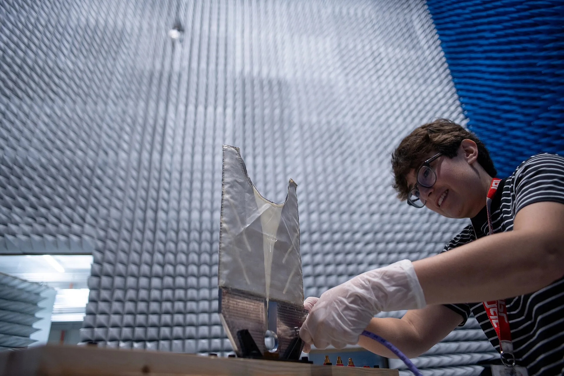 An engineer adjusting an antenna inside an anechoic chamber