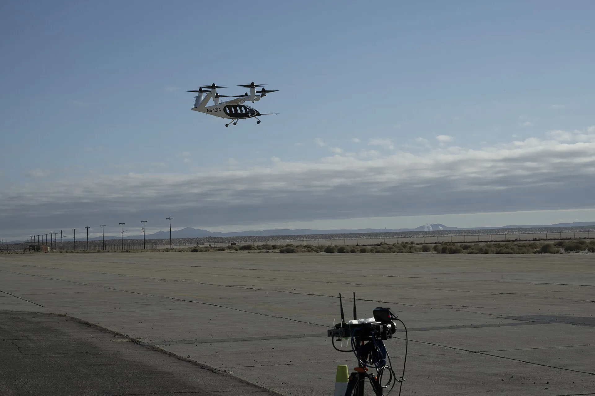An electric air taxi in flight above a tracking station in the desert