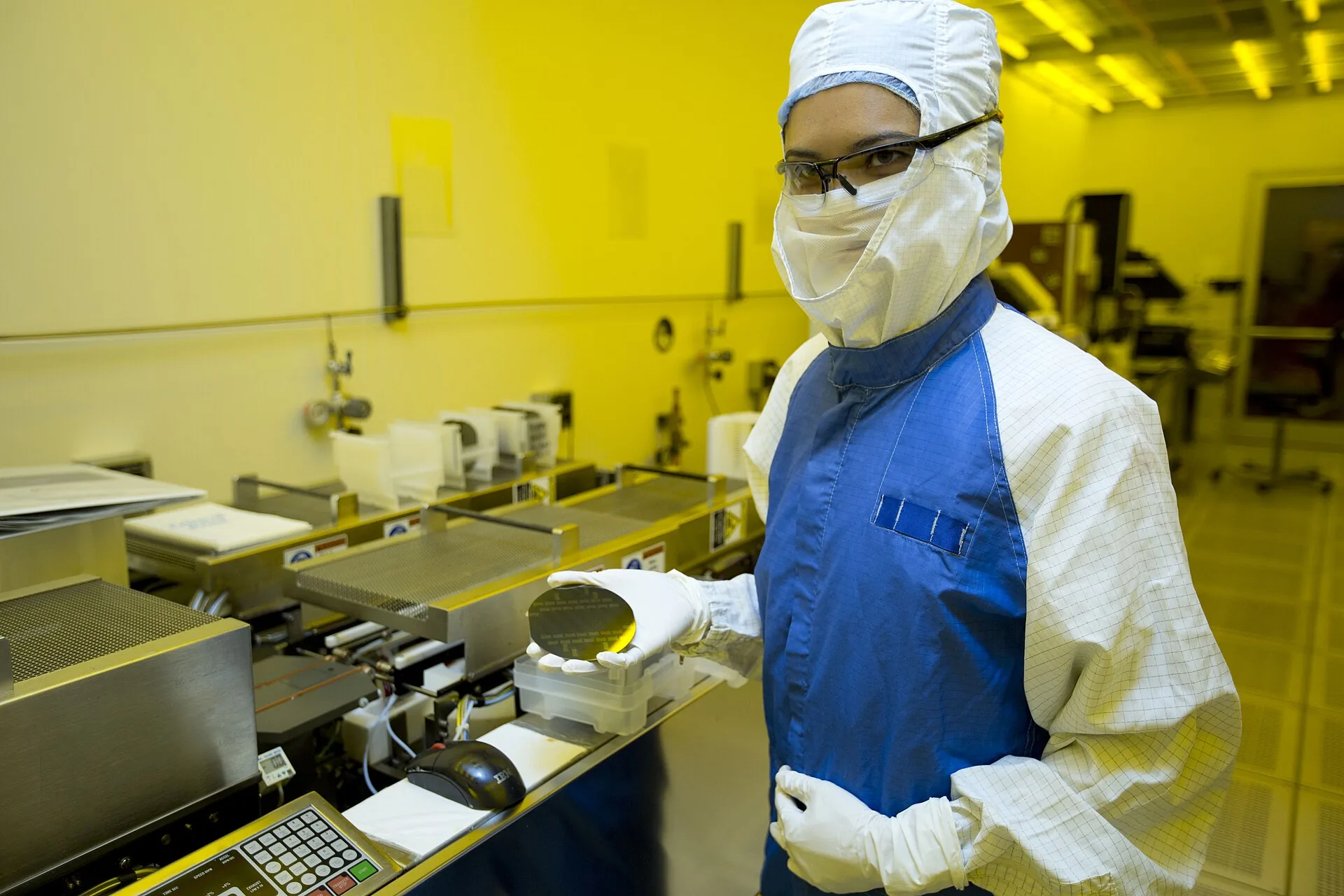 A researcher holding a silicon wafer in a clean room